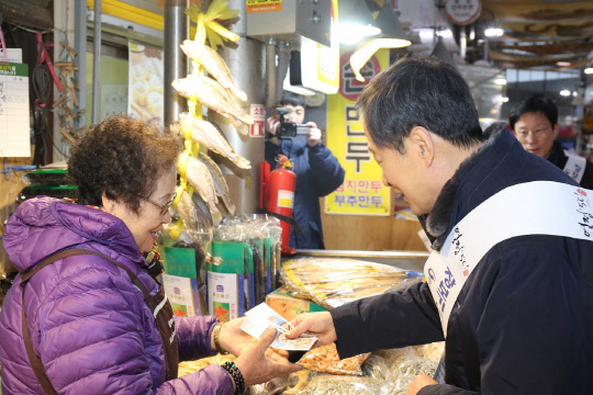 지난 13일 서울 종로 통인시장을 찾은 김흥빈 소상공인시장진흥공단 이사장(오른쪽)이 온누리상품권으로 먹거리를 구매하고 있다. 소진공 제공
